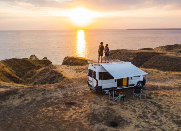 The Advantages and disadvantages of Buying New Electric Motor Residences for Sale Aerial view of heterosexual couple on roof of camper van on seaside  at sunset