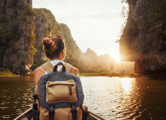 Adventure Travel in Vietnam woman with backpack traveling by boat enjoying sunset among of mountains.