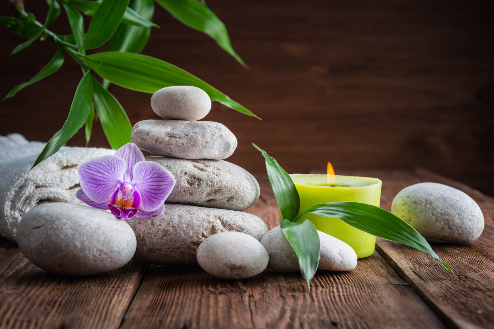 How to Build a Zen Garden White Zen balance stones, an Orchid flower, a bamboo plant and a candle on a wooden table